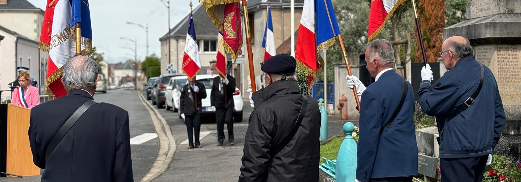 photo de la cérémonie du 18 juin, en 2024. Au premier plan les portes drapeaux à côté du monument aux morts